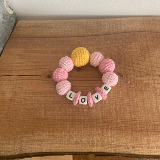 Hæklet bidering med perler i lyserødt og gult og bogstaver, der staver LOVE