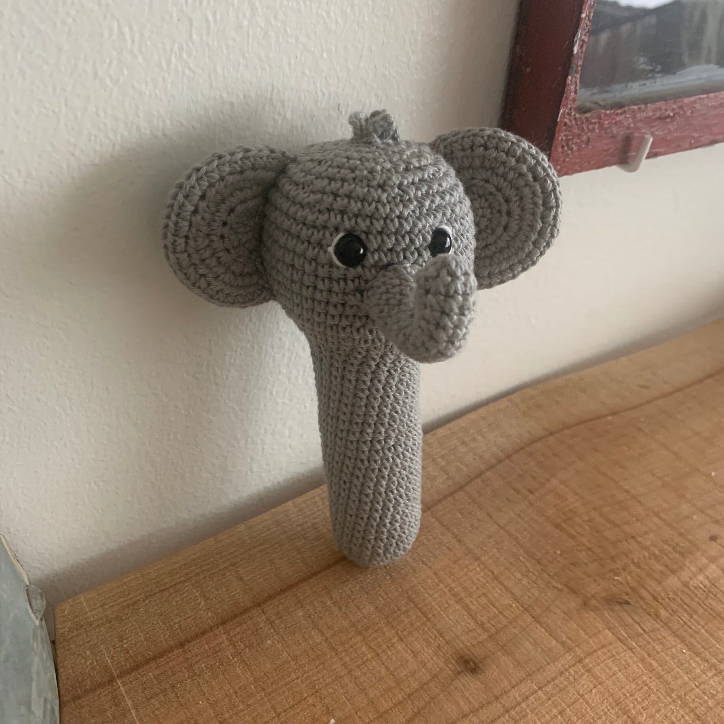 Hæklet elefant-rangle holdt i en hånd for at vise størrelsen