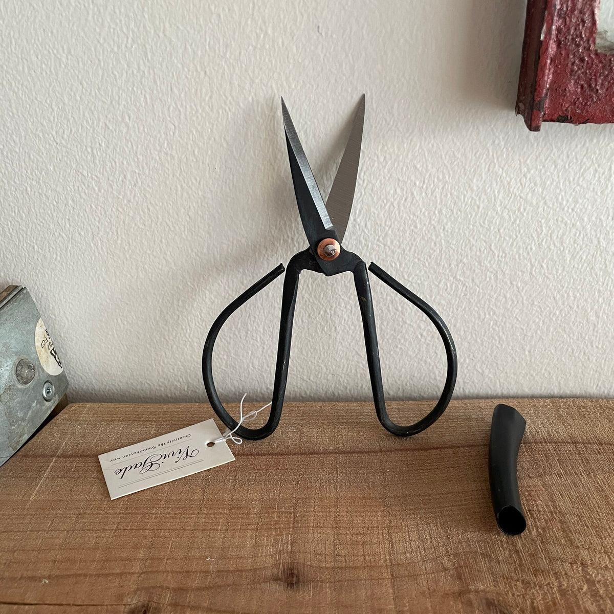 Gammeldags sort saks stående op ad væg med åbne blade