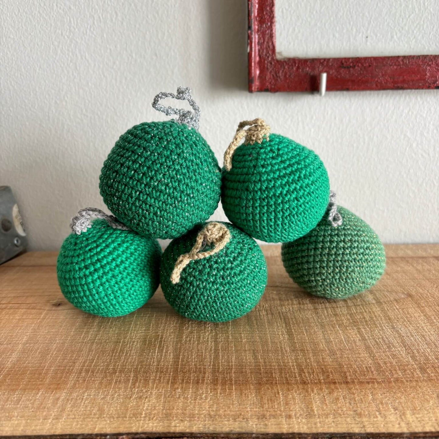 Fem hæklede julekugler i grøn, samlet