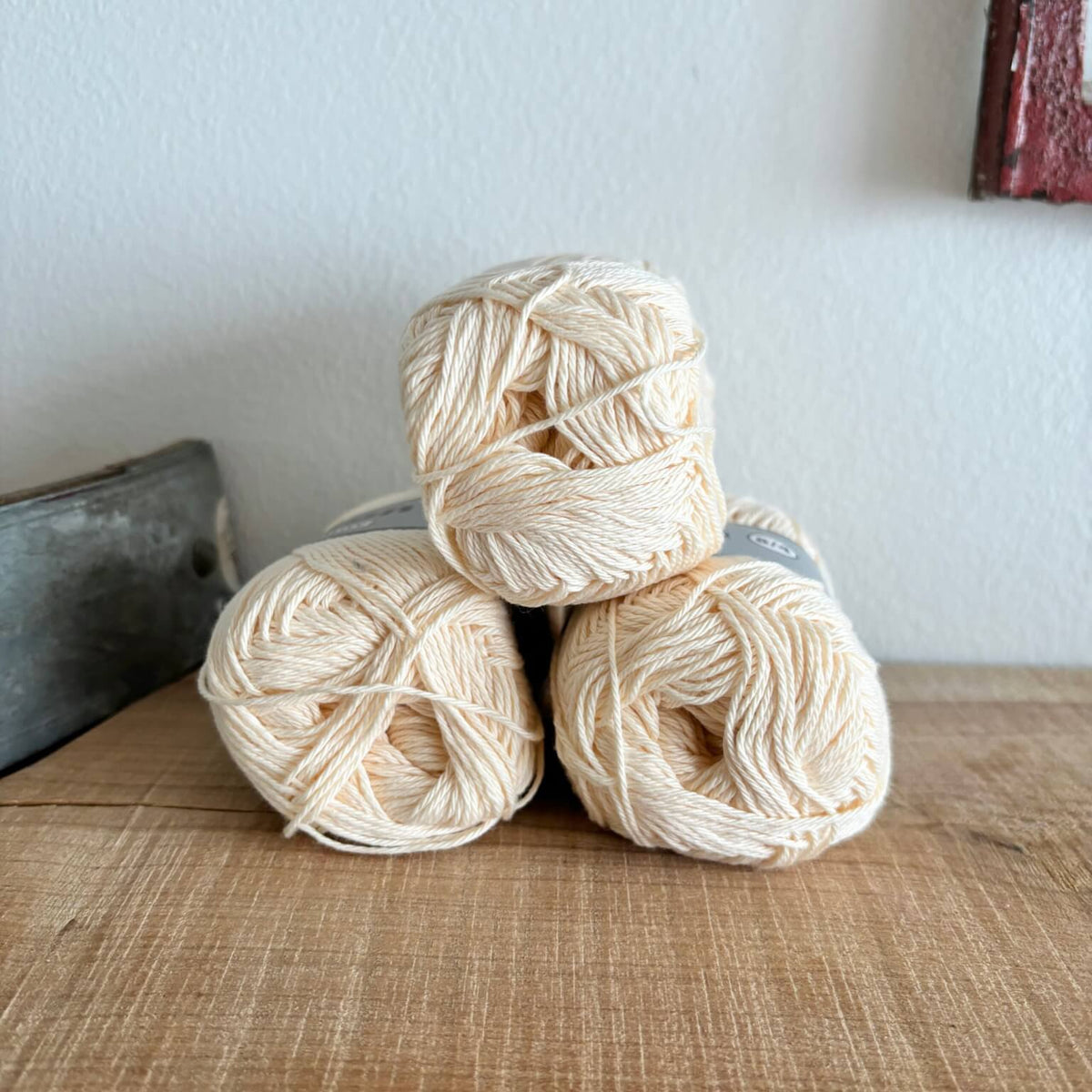 Tre garnnøgler Lammy Cotton 8/4 i vaniljefarve, stablet