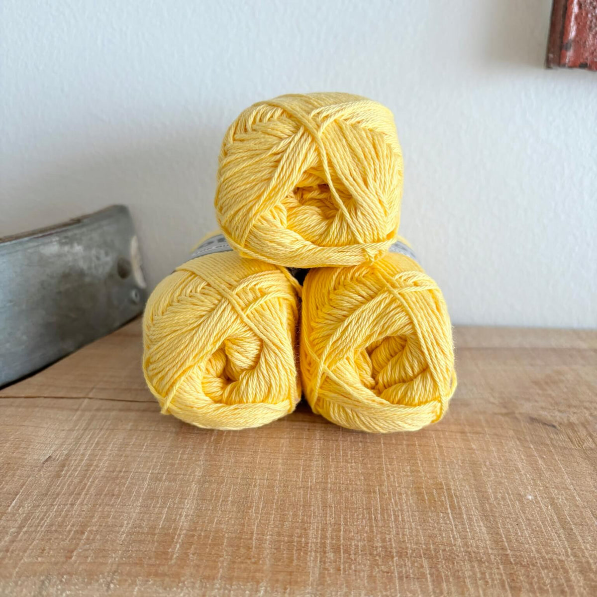 Tre garnnøgler Lammy Cotton 8/4 i lysegul, stablet