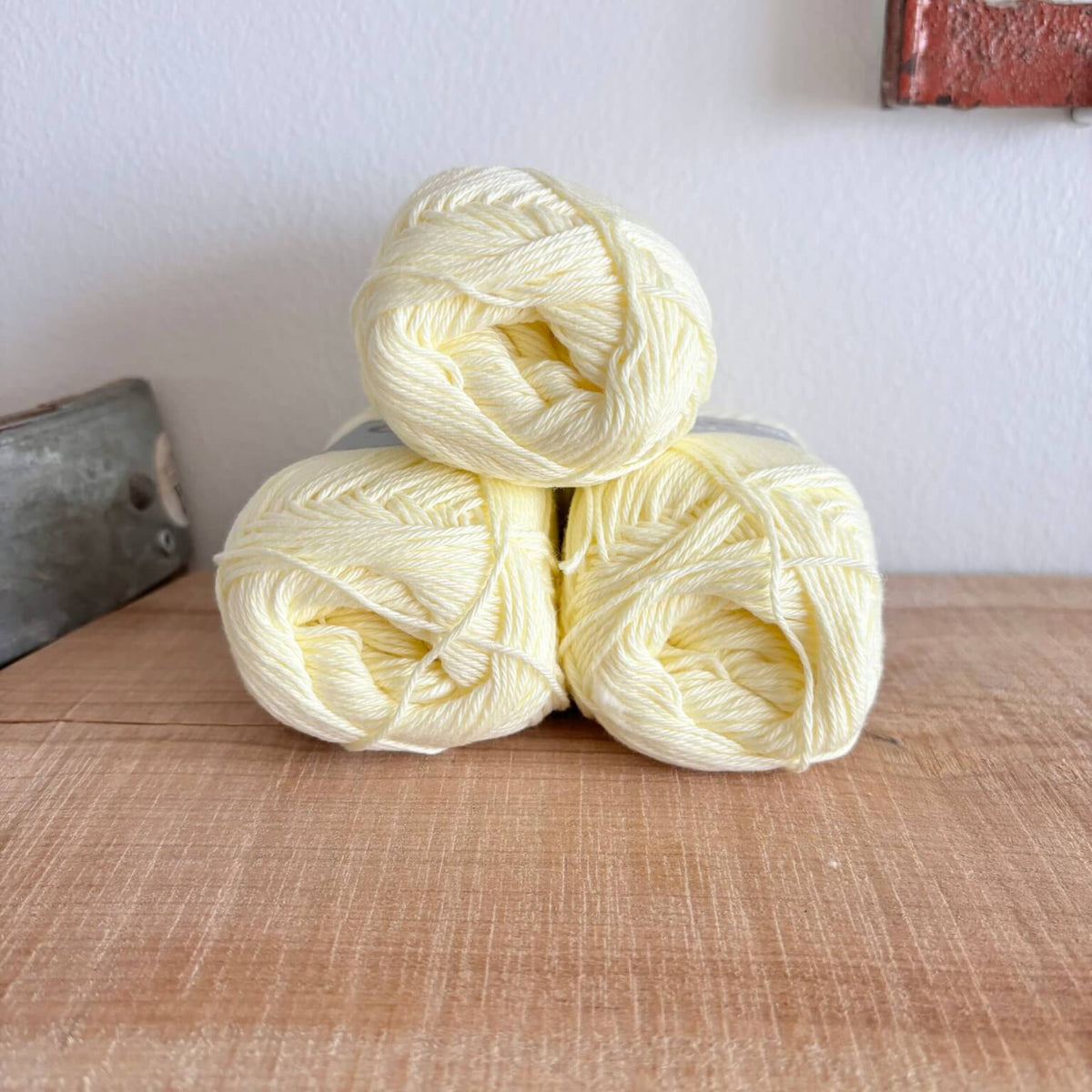 Tre garnnøgler Lammy Cotton 8/4 i pastelgult, stablet