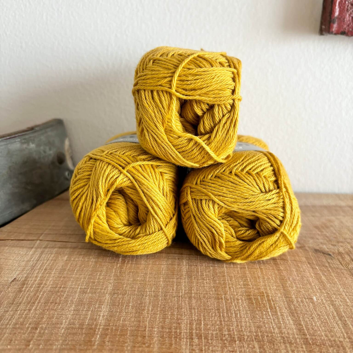 Tre garnnøgler Lammy Cotton 8/4 i karrygul, stablet