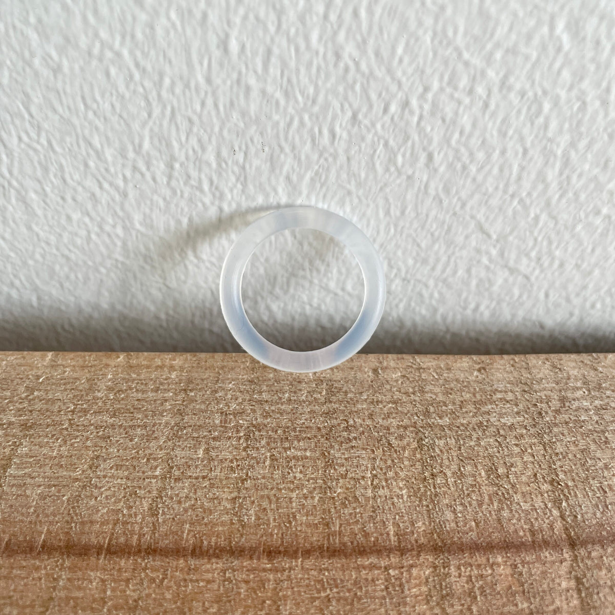 Transparent O-ring, enkelt, hængende foran hvid væg