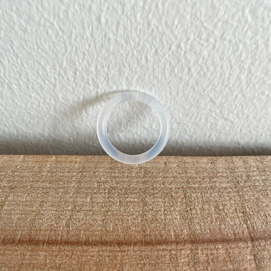Transparent O-ring, enkelt, hængende foran hvid væg